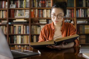A woman researches a book in a library.